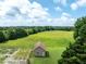 Aerial shot showing an auxillary building surrounded by a large field and lush trees on the property at 1502 Campground Rd, Mcdonough, GA 30252