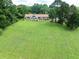 Expansive rear lawn with a brick home featuring a patio area and mature trees for privacy at 1502 Campground Rd, Mcdonough, GA 30252