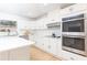White kitchen with stainless steel appliances, white countertops, white cabinets, and hardwood flooring at 1502 Campground Rd, Mcdonough, GA 30252