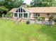 View of the rear of the house with brick accents, a sunroom, and a spacious green lawn at 1502 Campground Rd, Mcdonough, GA 30252