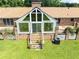 View of the rear exterior with a sunroom, deck, and staircase leading to the green lawn at 1502 Campground Rd, Mcdonough, GA 30252