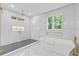 Contemporary bathroom with marble walls, a glass shower, and a freestanding soaking tub beneath a window at 2060 North Avenue Nw, Atlanta, GA 30318