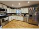 Bright kitchen with stainless steel appliances, white cabinets, and warm hardwood floors at 3034 Kent Ct, Duluth, GA 30096