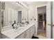 Bright bathroom with a double vanity, large mirror with Hollywood lighting, and an open view of the staircase at 3223 Thornecreek Dr, Douglasville, GA 30135