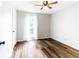 A sunny bedroom with wood-look flooring, neutral walls, and a large window with white curtains at 674 Crespan Ct, Lawrenceville, GA 30044