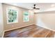 Sunlit bedroom featuring laminate flooring, a ceiling fan, and two windows with wooded views at 674 Crespan Ct, Lawrenceville, GA 30044