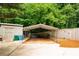 View of carport and storage shed with green bins, nestled among trees and vegetation at 674 Crespan Ct, Lawrenceville, GA 30044