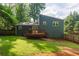 Home's exterior with a wooden deck and a grassy backyard, surrounded by trees at 674 Crespan Ct, Lawrenceville, GA 30044