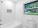 Clean and bright bathroom showcases a white tiled shower, toilet, and a window providing natural light at 2720 Cavalier Dr, Decatur, GA 30034
