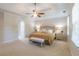 Spacious main bedroom with tray ceiling, fan, bench and carpeted floors at 366 Coopers Pond Dr, Lawrenceville, GA 30044