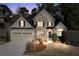 Charming two-story home featuring stone accents and a well-manicured front lawn at dusk with landscape lighting at 994 Fairview Club Cir, Dacula, GA 30019