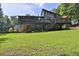 Lush backyard showcasing the house with a multi-tiered deck, large lawn, and ample shade trees at 3491 Birchwood Trl, Snellville, GA 30078