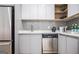 Modern kitchen featuring white cabinetry, stainless steel appliances, a grey backsplash, and open shelving at 3831 Flakes Mill Rd, Decatur, GA 30034