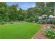 Beautiful backyard featuring a lush lawn, mature trees, and a cozy deck with seating area at 7108 Hummingbird Ln, Winston, GA 30187