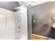 Bathroom featuring a shower with gray accent wall, and brown faux wood flooring at 7108 Hummingbird Ln, Winston, GA 30187