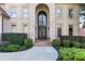 Close-up of the grand front entrance, featuring an arched doorway, brick accents, and manicured greenery at 8430 Merion Drive, Duluth, GA 30097
