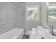 Modern bathroom with marble-look tile, white fixtures, and a window at 1641 Rockcliff Se Pl, Atlanta, GA 30316