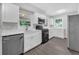 Modern white kitchen with stainless steel appliances, white cabinets, and gray wood floors at 1641 Rockcliff Se Pl, Atlanta, GA 30316