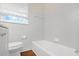 Bathroom showcasing tub and toilet with window and white wall tiling at 2683 Rockcliff Se Rd, Atlanta, GA 30316