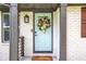 Charming front door features a teal door with a floral wreath and a brick surround, enhancing curb appeal at 3093 Del Monico Dr, Decatur, GA 30032