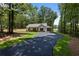 Charming single-story home with an extended driveway and a covered carport, surrounded by lush greenery at Lot 2 Harmony Rd, Temple, GA 30179
