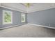 A spacious bedroom has plush carpet, a ceiling fan, and natural light from two large windows at 2333 Old Newnan Rd, Carrollton, GA 30116