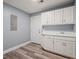 Laundry room with white cabinets, sink, and updated flooring at 2333 Old Newnan Rd, Carrollton, GA 30116