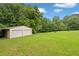 Outbuilding with garage doors in the backyard on a lot with green grass and plentiful trees at 2333 Old Newnan Rd, Carrollton, GA 30116