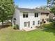 A white two-story home features a dark roof, green lawn and small backyard patio at 3063 Broadleaf Trl, Fairburn, GA 30213