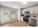 Modern kitchen equipped with stainless steel appliances, white cabinetry, and convenient access to the backyard at 3063 Broadleaf Trl, Fairburn, GA 30213