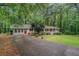 A single story home's long driveway leads to a classic exterior with a covered porch amidst a lush, wooded landscape at 5317 Highway 81, Loganville, GA 30052