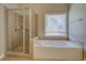 Bright bathroom featuring a glass shower and soaking tub under a window at 1065 Chippewa Oak Dr, Dacula, GA 30019