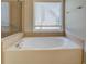 Close up of the soaking tub under a window with a tiled wall and glass enclosed shower at 1065 Chippewa Oak Dr, Dacula, GA 30019