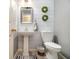 Cozy bathroom with pedestal sink, updated fixtures, decorative wreaths, and modern toilet at 110 Windsor Chase Dr, Lawrenceville, GA 30043