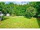 Spacious backyard with lush lawn, mature trees, playground, storage sheds, and inviting fire pit at 5388 Silver Springs Dr, Sugar Hill, GA 30518