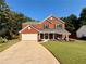 Charming two-story red brick home with an attached garage and well-manicured lawn at 5388 Silver Springs Dr, Sugar Hill, GA 30518