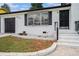 Close-up view of a charming white brick home with black-framed windows, a well-manicured lawn, and a paved walkway at 2403 Tiffany Pl, Decatur, GA 30035