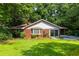 Charming brick home featuring a well-manicured lawn, mature trees, and a concrete driveway at 1102 Rogeretta Ne Dr, Atlanta, GA 30329