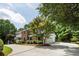 Brick home with a lovely front porch and a long, paved driveway flanked by lush greenery and mature trees at 4047 Dunwoody Club Dr, Dunwoody, GA 30350