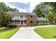 Inviting brick home featuring a classic colonial design, a double-decker porch, and professionally landscaped front yard at 4047 Dunwoody Club Dr, Dunwoody, GA 30350