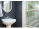 Chic powder room featuring a pedestal sink, a round mirror and a window at 827 Perennial Dr, Atlanta, GA 30328