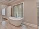 Bright bathroom with a freestanding tub, light tile flooring, and large window at 1169 Dorby Park Ne Dr, Brookhaven, GA 30319
