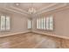 Bright bedroom featuring tray ceilings, hardwood floors, large windows with plantation shutters, and a crystal chandelier at 1169 Dorby Park Ne Dr, Brookhaven, GA 30319