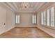 Bedroom featuring tray ceilings, a chandelier, hardwood floors, and large windows with plantation shutters at 1169 Dorby Park Ne Dr, Brookhaven, GA 30319