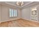 Bedroom features wood floors, neutral walls, tray ceiling with chandelier, and view into ensuite bathroom at 1169 Dorby Park Ne Dr, Brookhaven, GA 30319