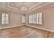 Elegant bedroom with tray ceilings, hardwood floors, a crystal chandelier, and lots of natural light from shuttered windows at 1169 Dorby Park Ne Dr, Brookhaven, GA 30319