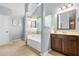 Well-lit bathroom with a soaking tub, wooden vanity, framed mirror, and soothing paint, blending functionality with a relaxing vibe at 364 Mossycup Dr, Fairburn, GA 30213