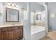 Spacious bathroom with a soaking tub, wooden vanity, framed mirror, and a window offering natural light, promoting relaxation at 364 Mossycup Dr, Fairburn, GA 30213