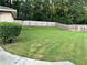 A large manicured lawn with a fenced perimeter and a brick home in the background at 3845 Pebble Beach Dr, Atlanta, GA 30349