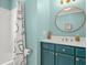 Stylish aqua bathroom with tub and shower combo, vanity, and round mirror at 877 Mclendon Dr, Scottdale, GA 30079
